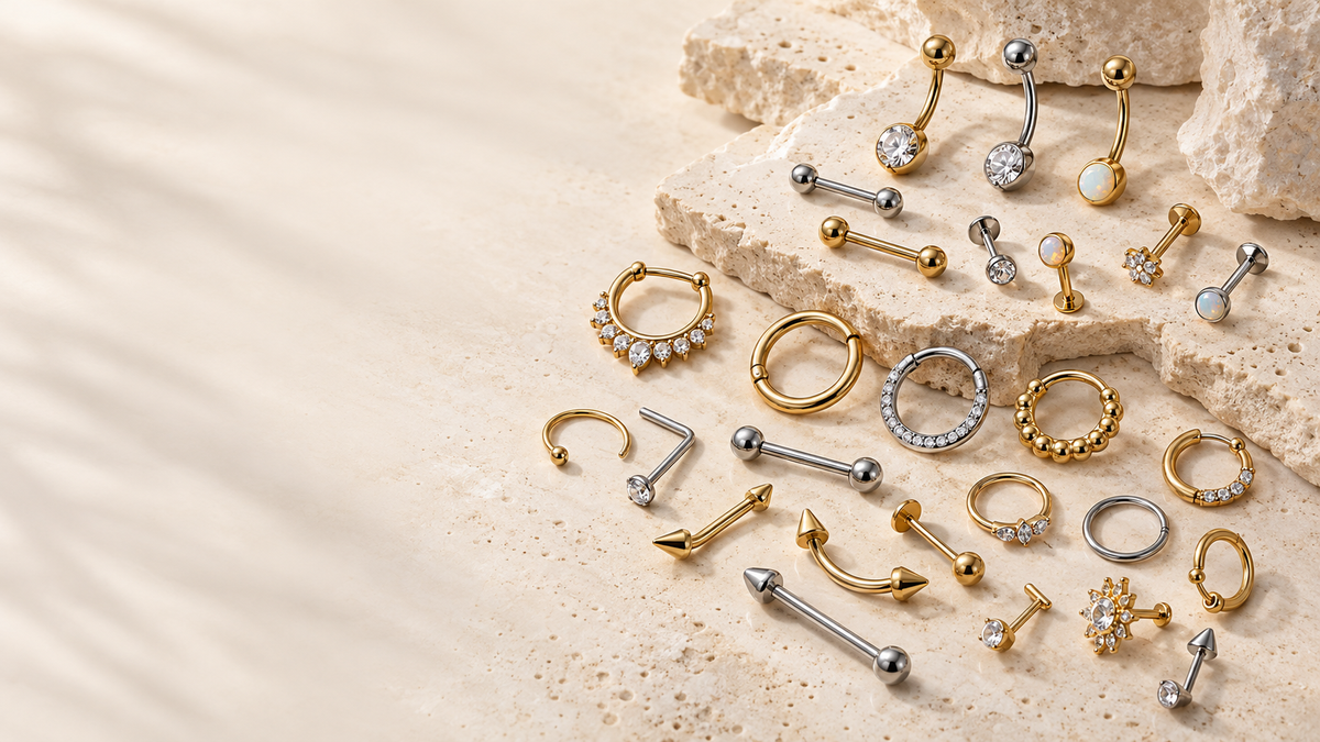 Studio arrangement of assorted body piercing jewelry on pale stone